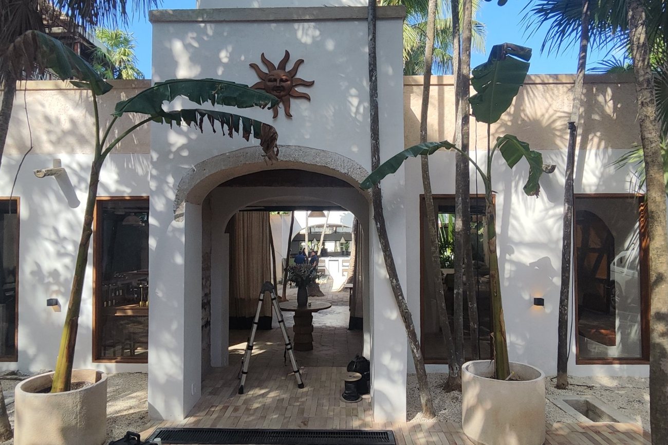 Entrada de Check Point Ciao Osteria en Tulum, con arco, palmeras y plátanos