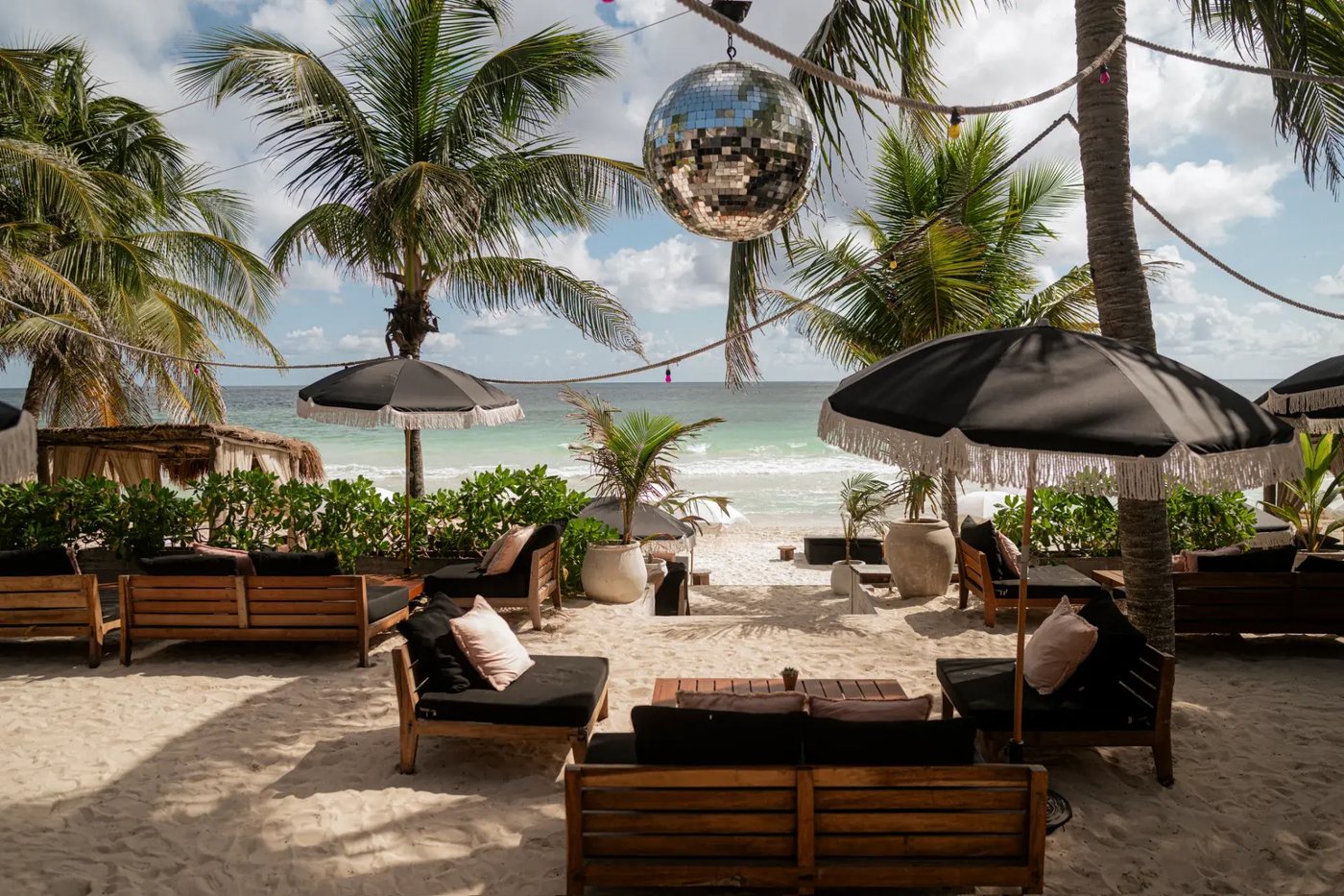 Lounge de Gitano Beach sobre la arena, con bola de espejos y el mar de Tulum al fondo