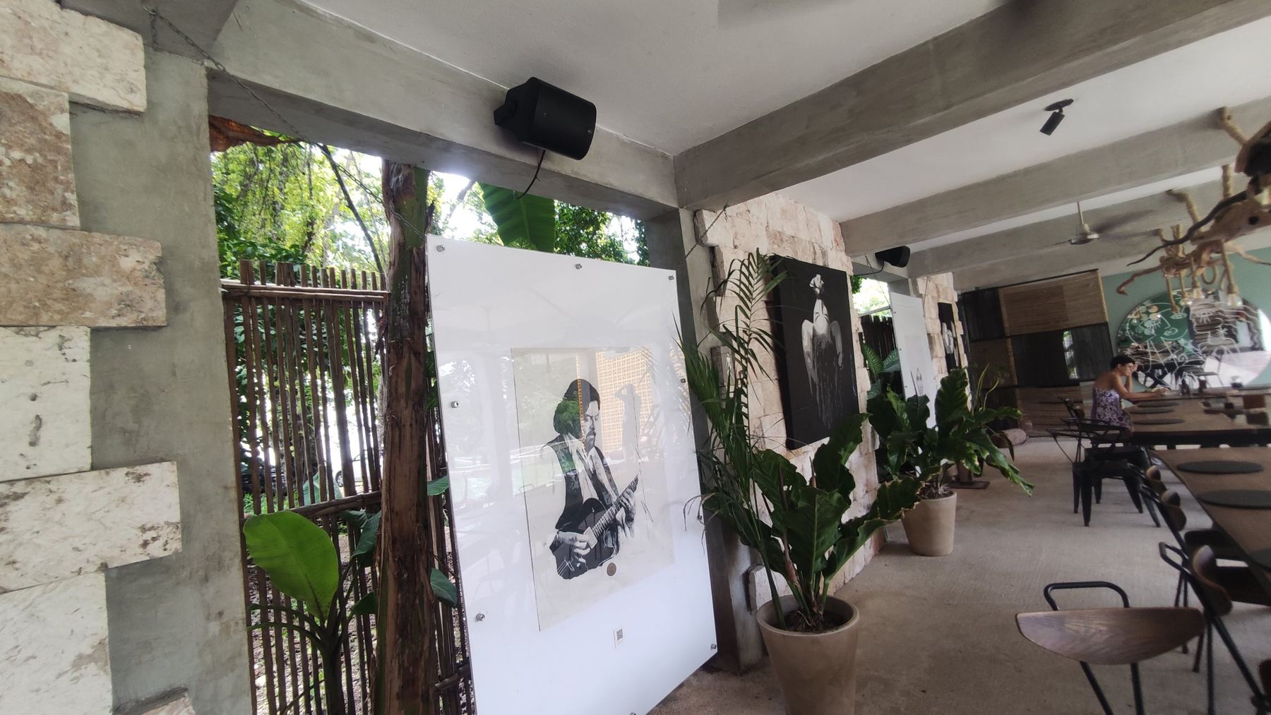 Terraza techada con obras de arte y bocinas montadas en las vigas