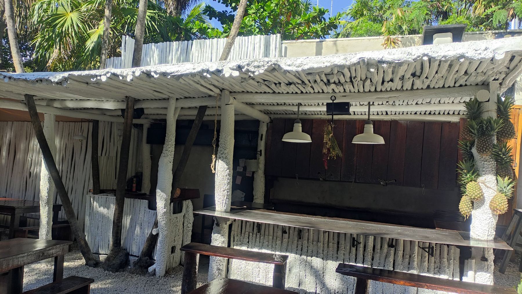 Bar al aire libre con techo de madera blanca y bocina sobre la barra