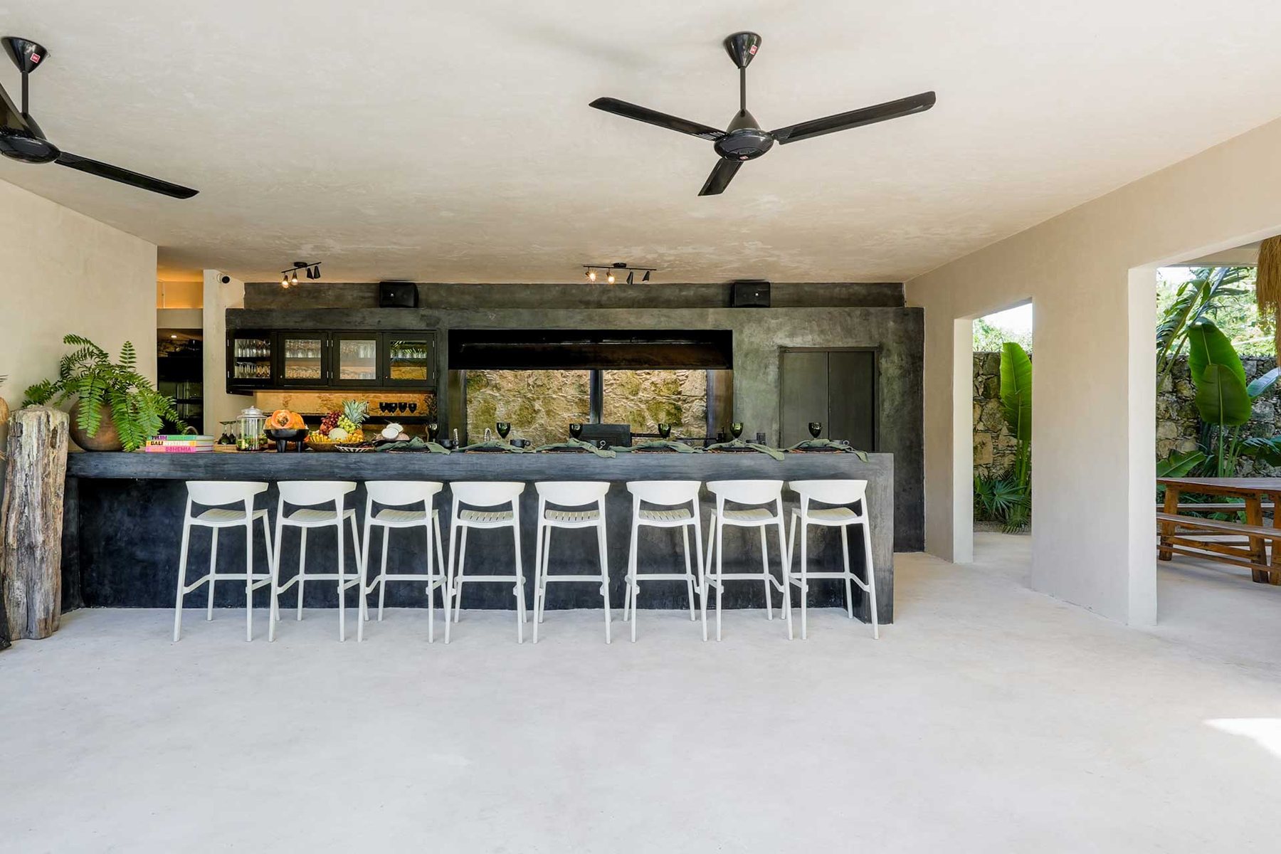 Barra de cocina con bancos blancos y bocinas sobre el muro