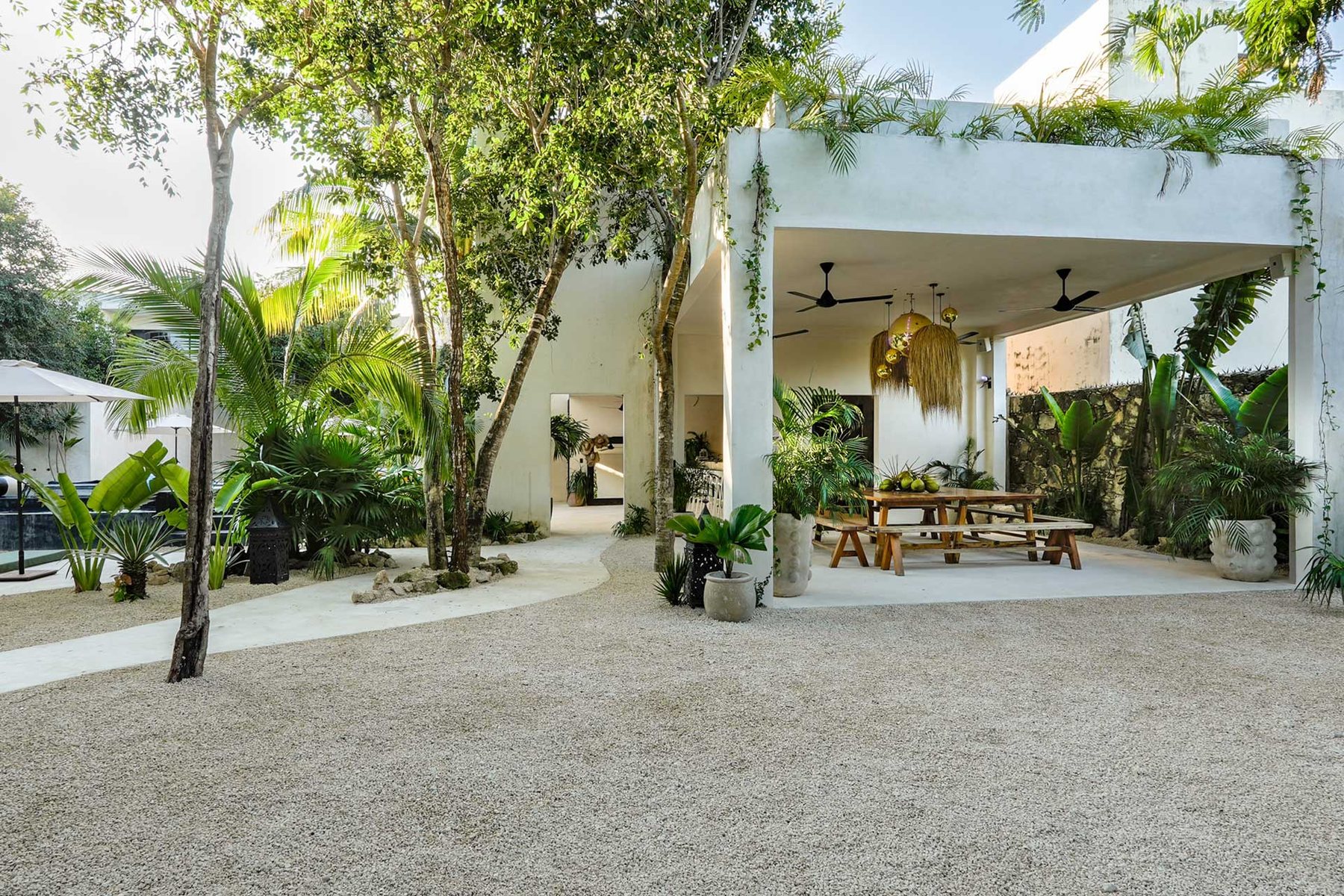 Jardín de grava y comedor techado con lámparas de palma