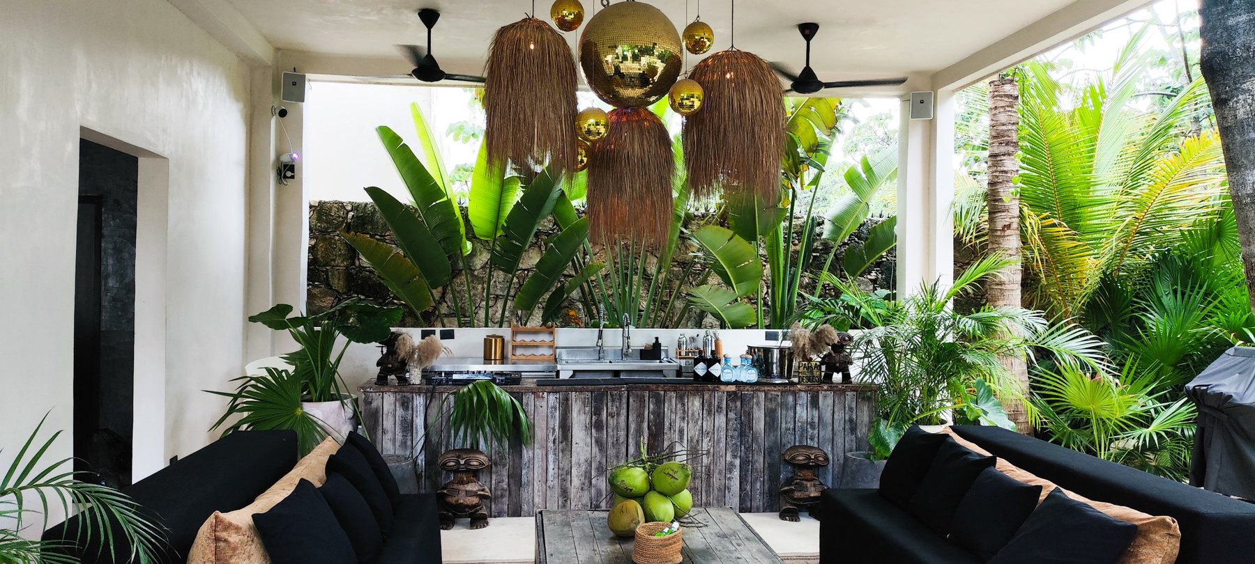 Lounge con barra, lámparas de palma y bocinas en las columnas