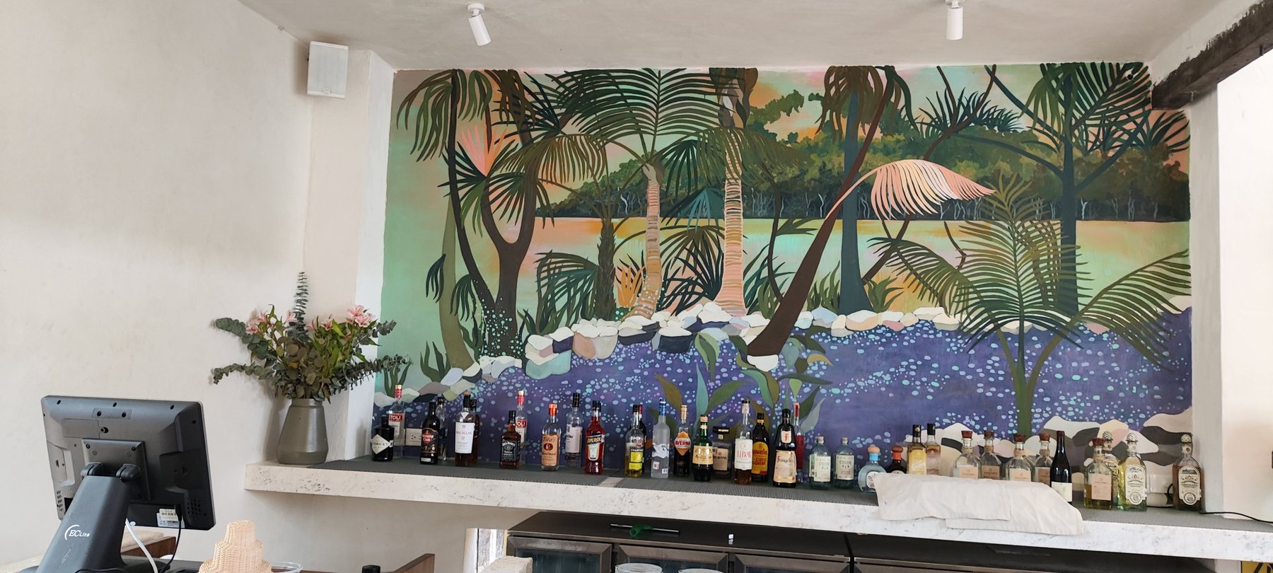 Barra con mural tropical y bocina blanca montada en el muro