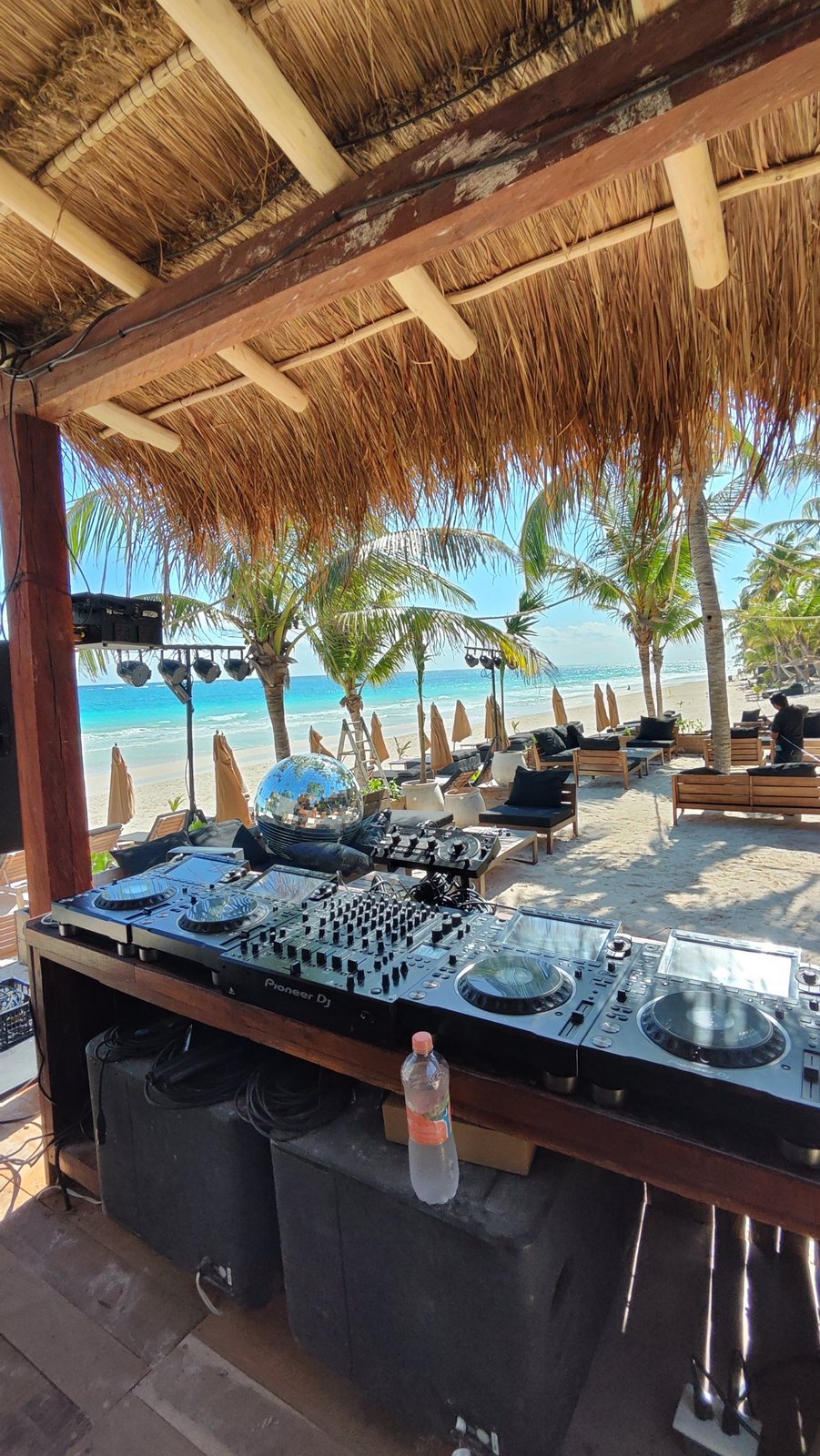 Equipo de DJ en la cabina con la playa y las luces al fondo