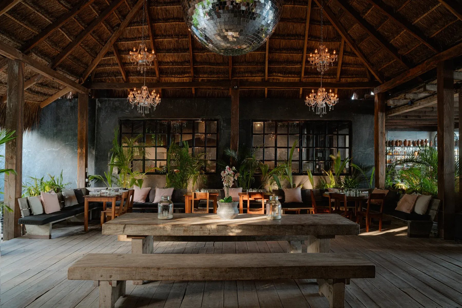 Restaurante bajo palapa con candelabros y bola de espejos
