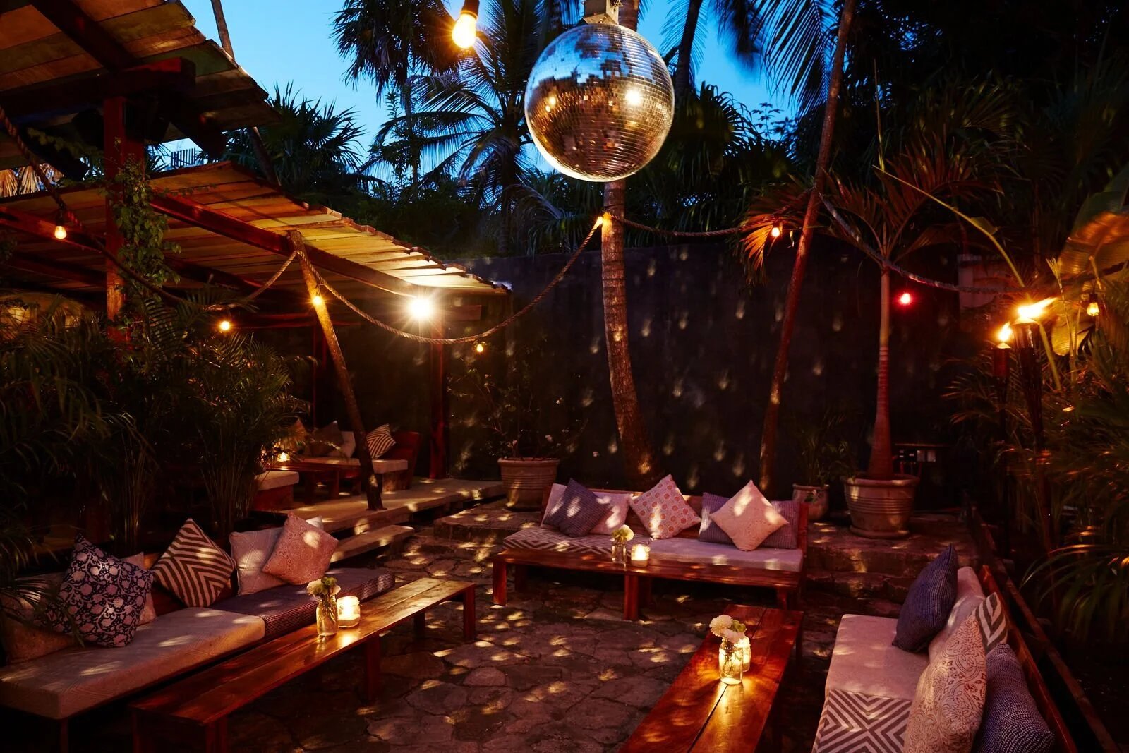 Lounge de noche con bola de espejos y antorchas