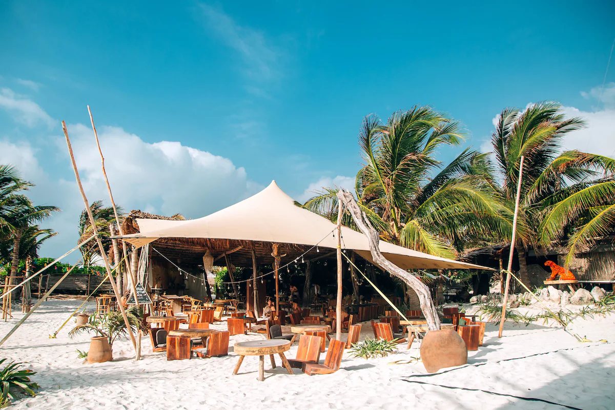Restaurante bajo carpa sobre la arena, entre palmeras