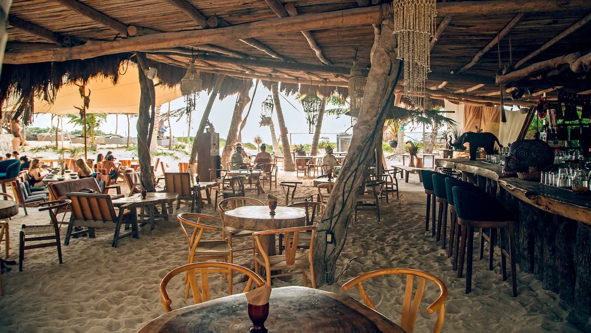 Restaurante de playa de Ikal con barra de madera, bajo techo de palma, abierto al mar
