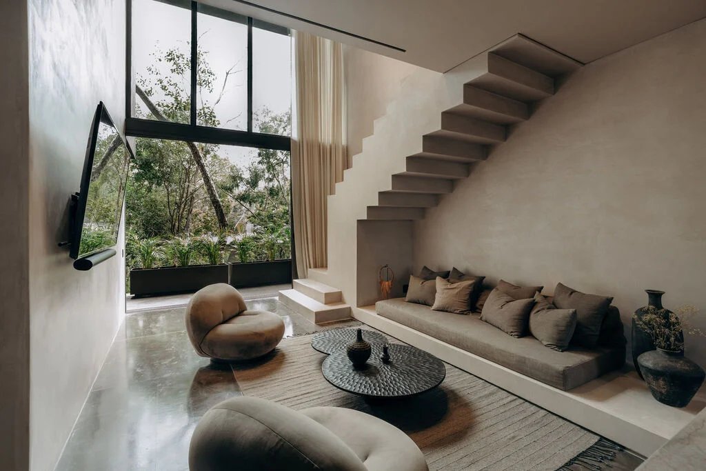 Sala de doble altura con escalera volada y ventanal a la selva
