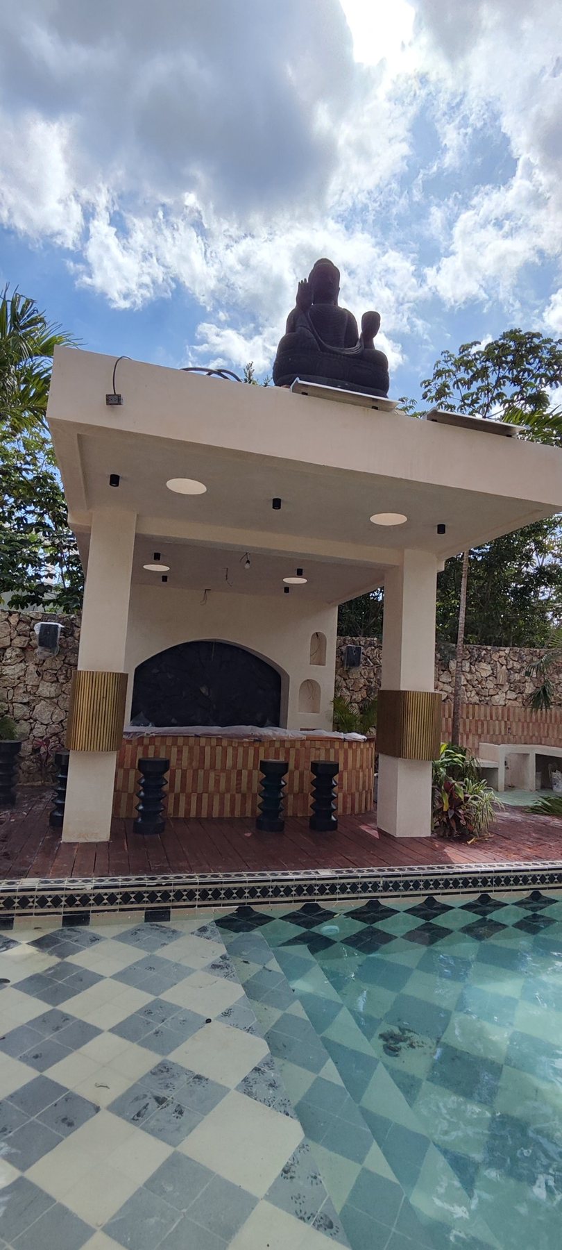 Pérgola junto a la alberca con bocinas de exterior en los muros de piedra