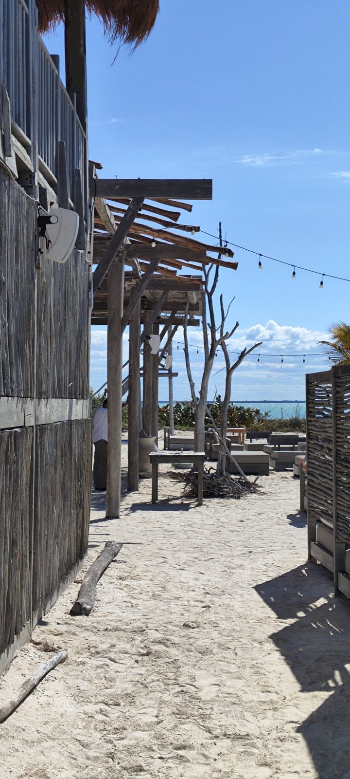 Bocinas blancas montadas en la pérgola de madera del beach club