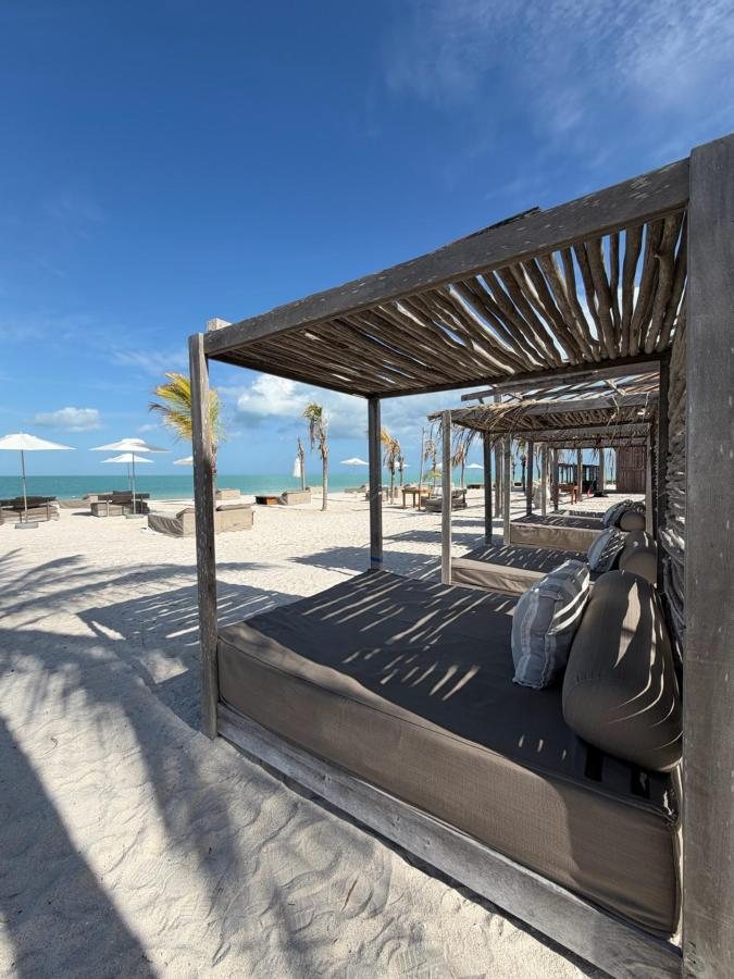 Camastro bajo pérgola de madera frente a la playa